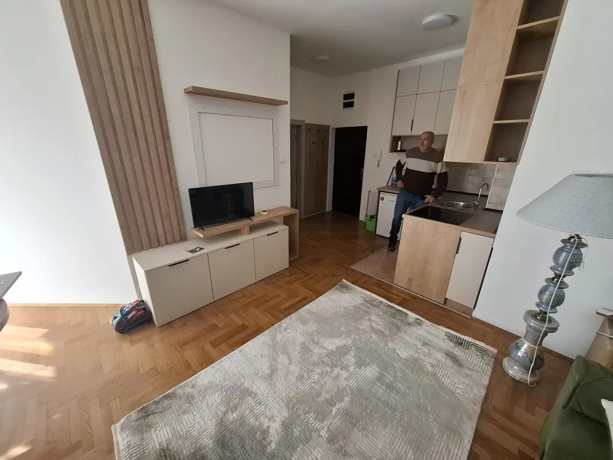Dnevna soba sa televizorom i pogledom prema kuhinji.