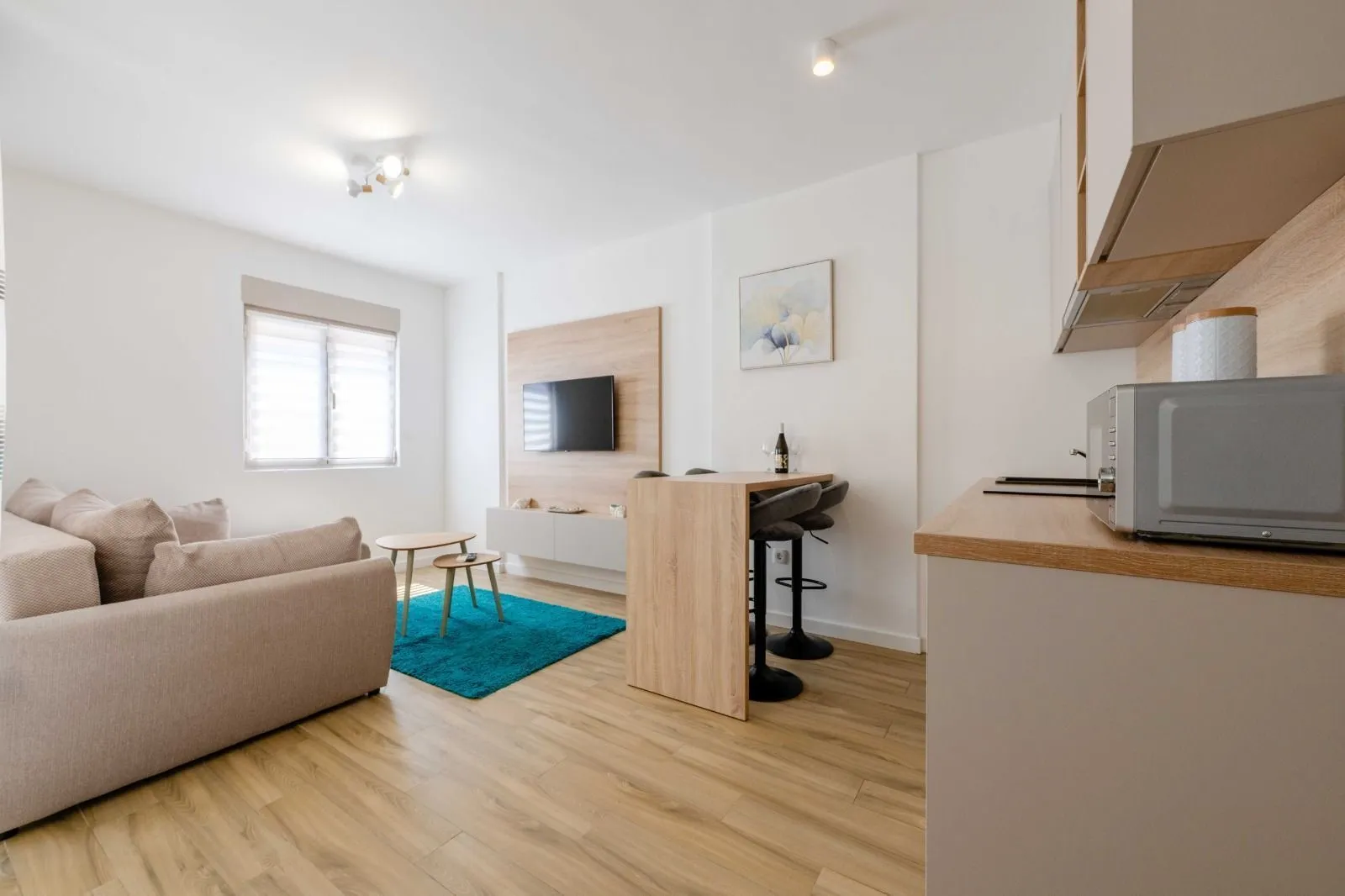 Living room with sofa, TV and dining area connected to the kitchen.