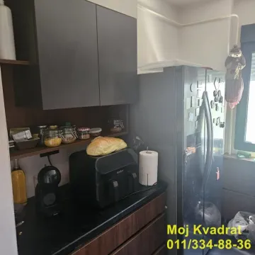 Deo kuhinje sa kuhinjskim elementima, frižiderom i radnom površinom. - image 3