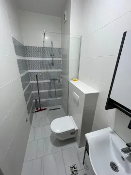 Modern bathroom with a shower cabin, wall-mounted toilet, and white tiles. - image 7