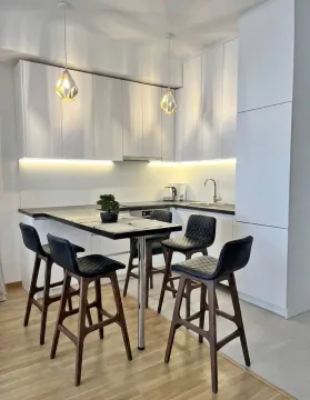 Modern white kitchen with a dining table and bar stools. - image 5
