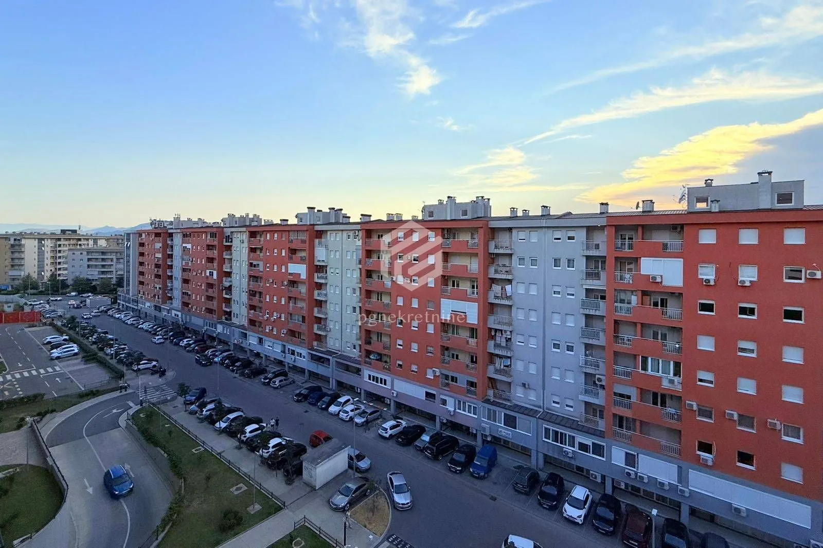 Pogled sa prozora na okolne zgrade i parking.