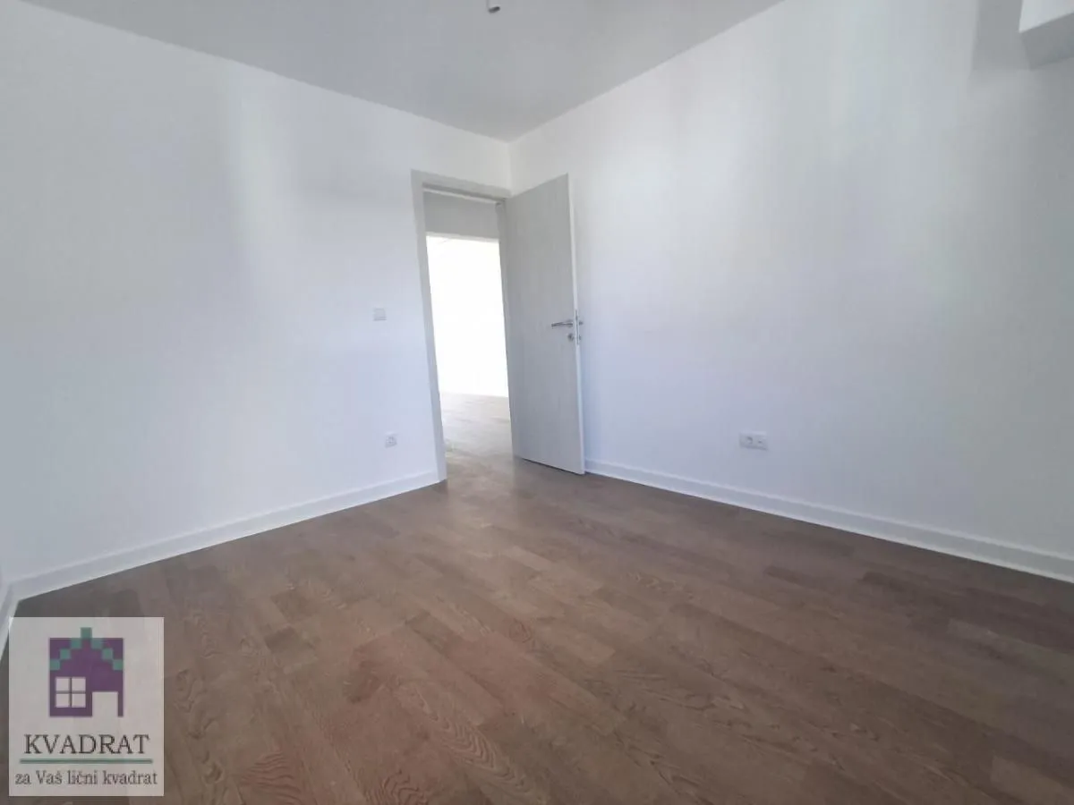 Empty room with wooden flooring and an open door.