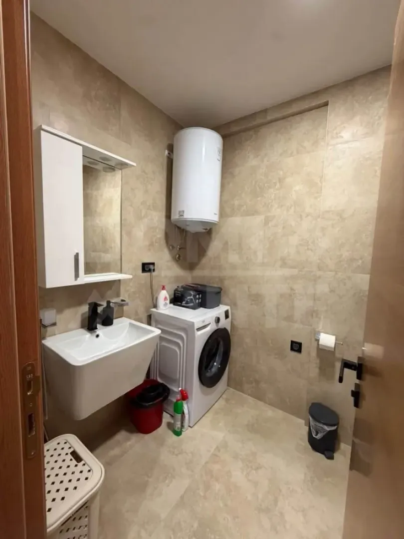Small bathroom with a shower, sink, and washing machine.