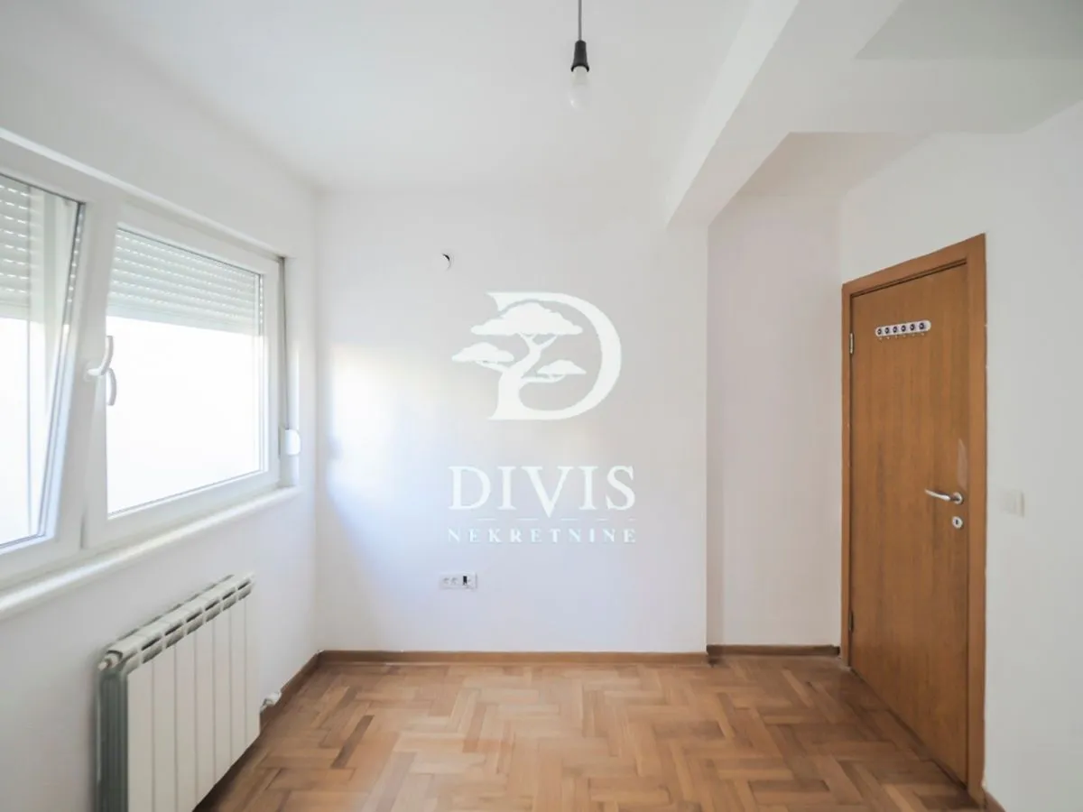 Empty room with parquet flooring, a window, and a wooden door.