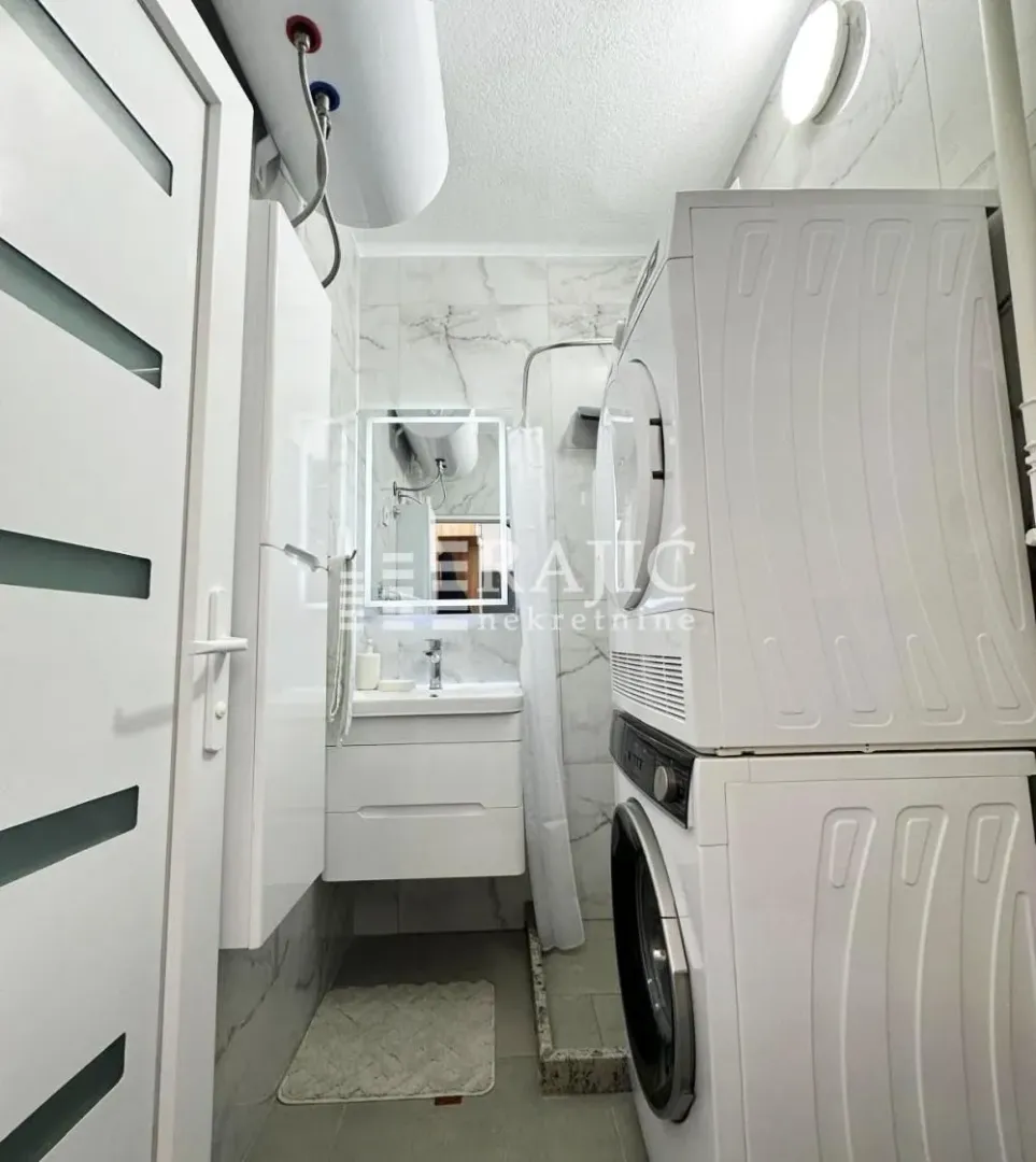 Small bathroom with a washing machine, shower cabin and washbasin.