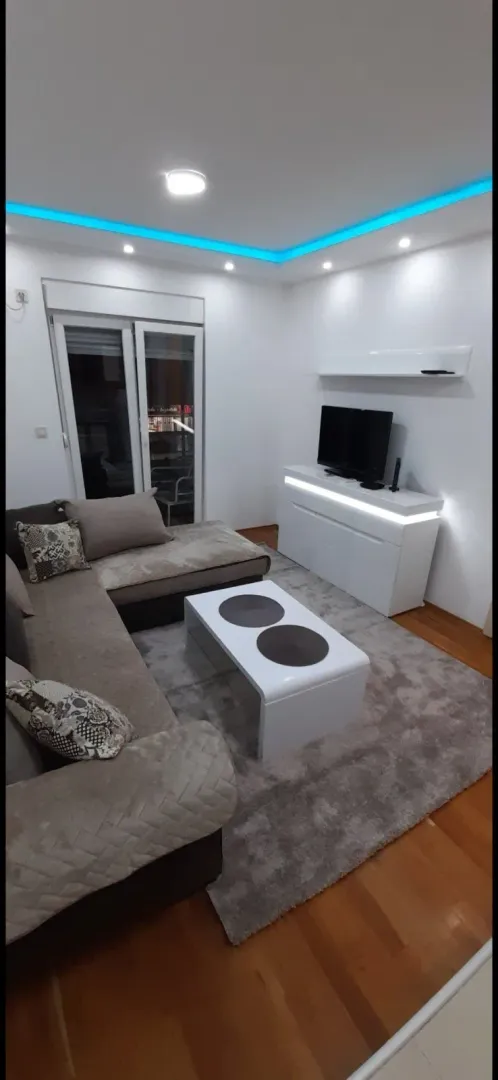 Svijetla dnevna soba sa ugaonom garniturom i modernom LED rasvjetom.