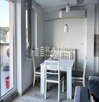 Dining area with a white table and chairs and access to the terrace. - image 3