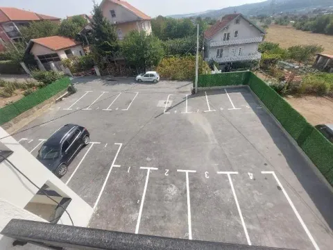 Ograđeni parking prostor sa označenim parking mestima. - image 11