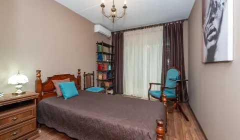 Furnished bedroom with a double bed, blue armchair, and bookshelf. - image 6