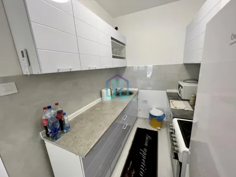 Compact kitchen with white wall cabinets and grey base cabinets. - image 4