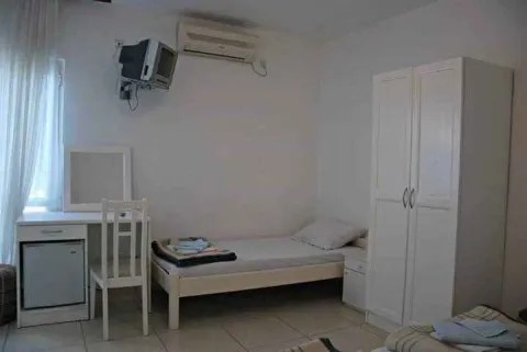 A simple bedroom featuring a single bed, a white wardrobe, and a desk. - image 8