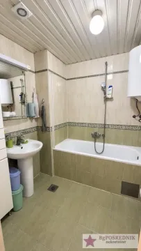 Bathroom equipped with a bathtub, washbasin, and tiled walls. - image 11