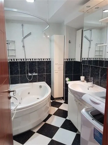 Svijetlo kupatilo sa đakuzi kadom, lavaboom i crno-bijelim pločicama.