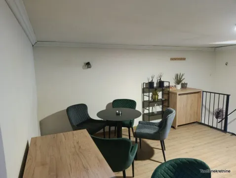 Small seating area with a round table and green armchairs. - image 6