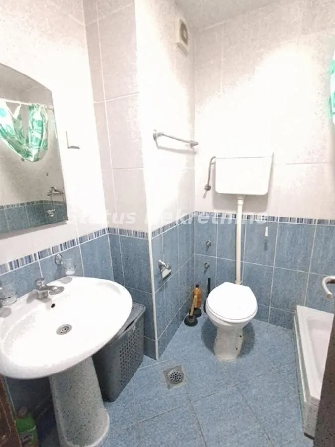 Manje kupatilo sa umivaonikom, WC šoljom i pločicama u plavim tonovima.