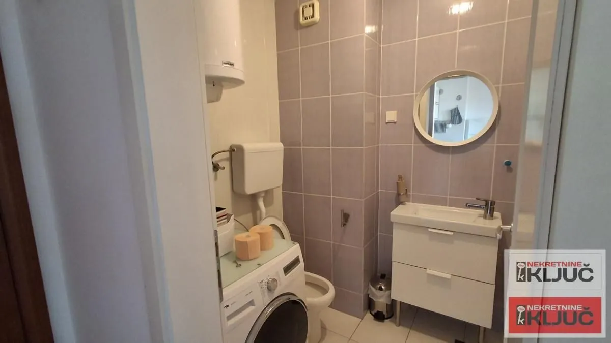 Manje kupatilo sa umivaonikom, WC šoljom, bojlerom i veš mašinom.