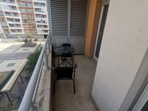 Balkon sa malim stolom i dvije stolice sa pogledom na okolne zgrade. - image 5