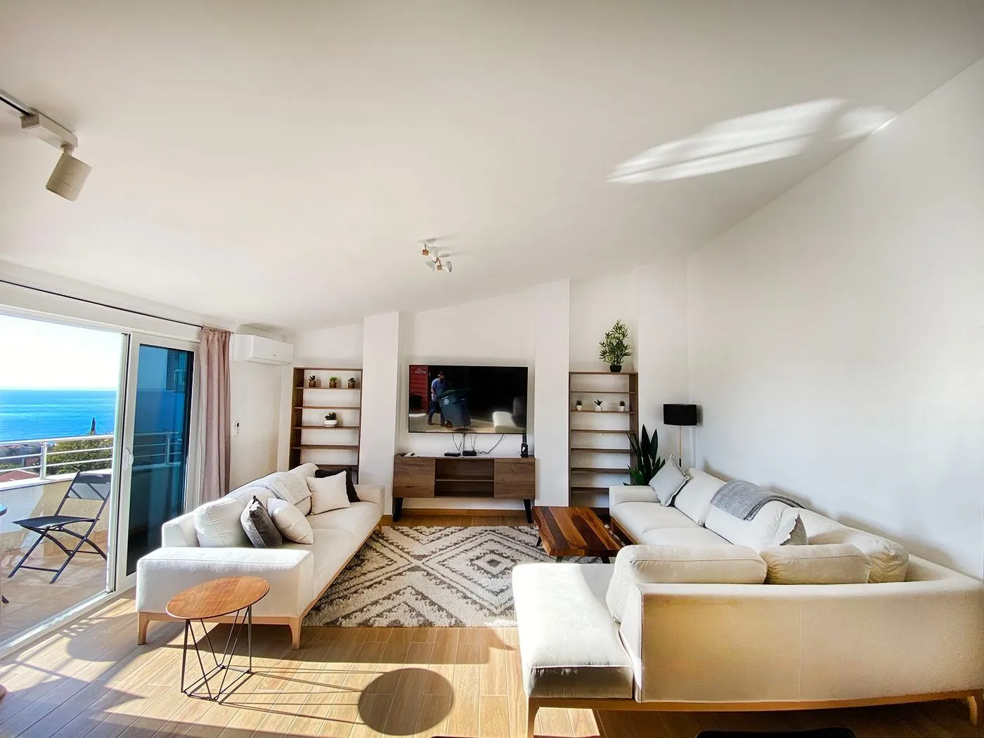 Spacious and bright living room with seating furniture and a sea view.