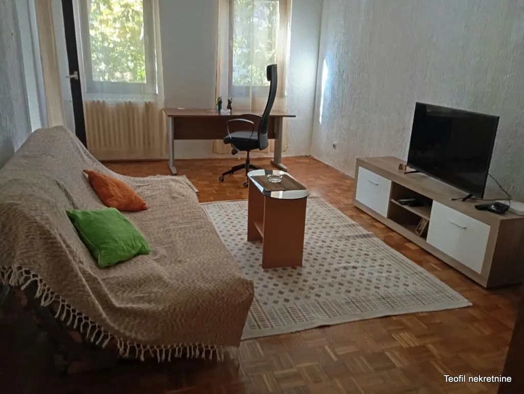 Living room equipped with a sofa, TV unit, and a desk.