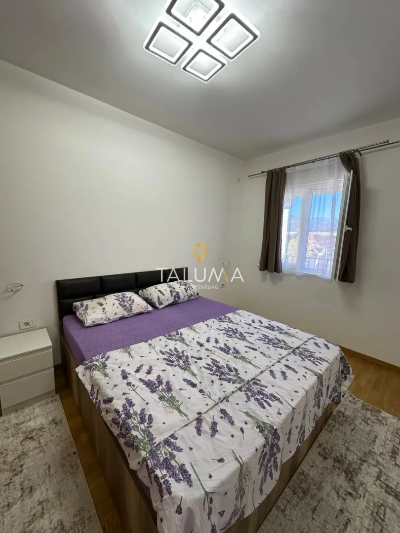 Namještena spavaća soba sa bračnim krevetom i prozorom.