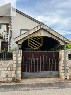 Eksterijer kuće sa kamenim ulaznim tremom i drvenom kapijom. - image 3