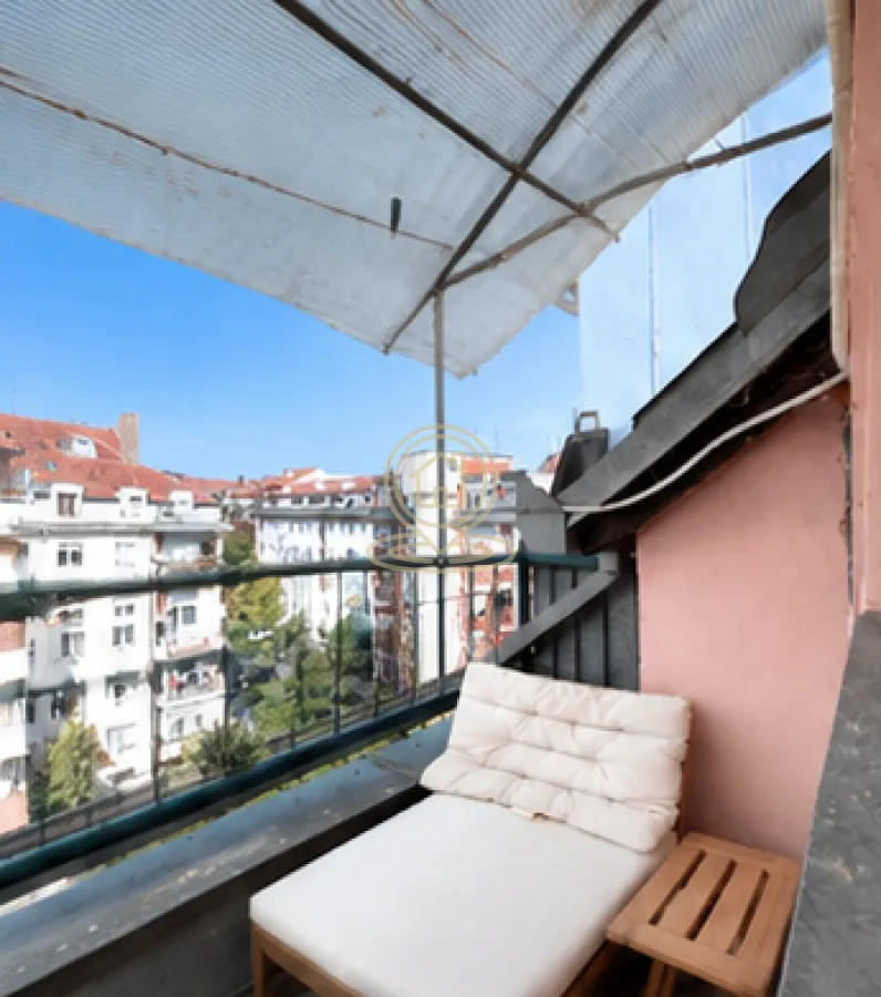 Natkriveni balkon sa ležaljkom i pogledom na grad.