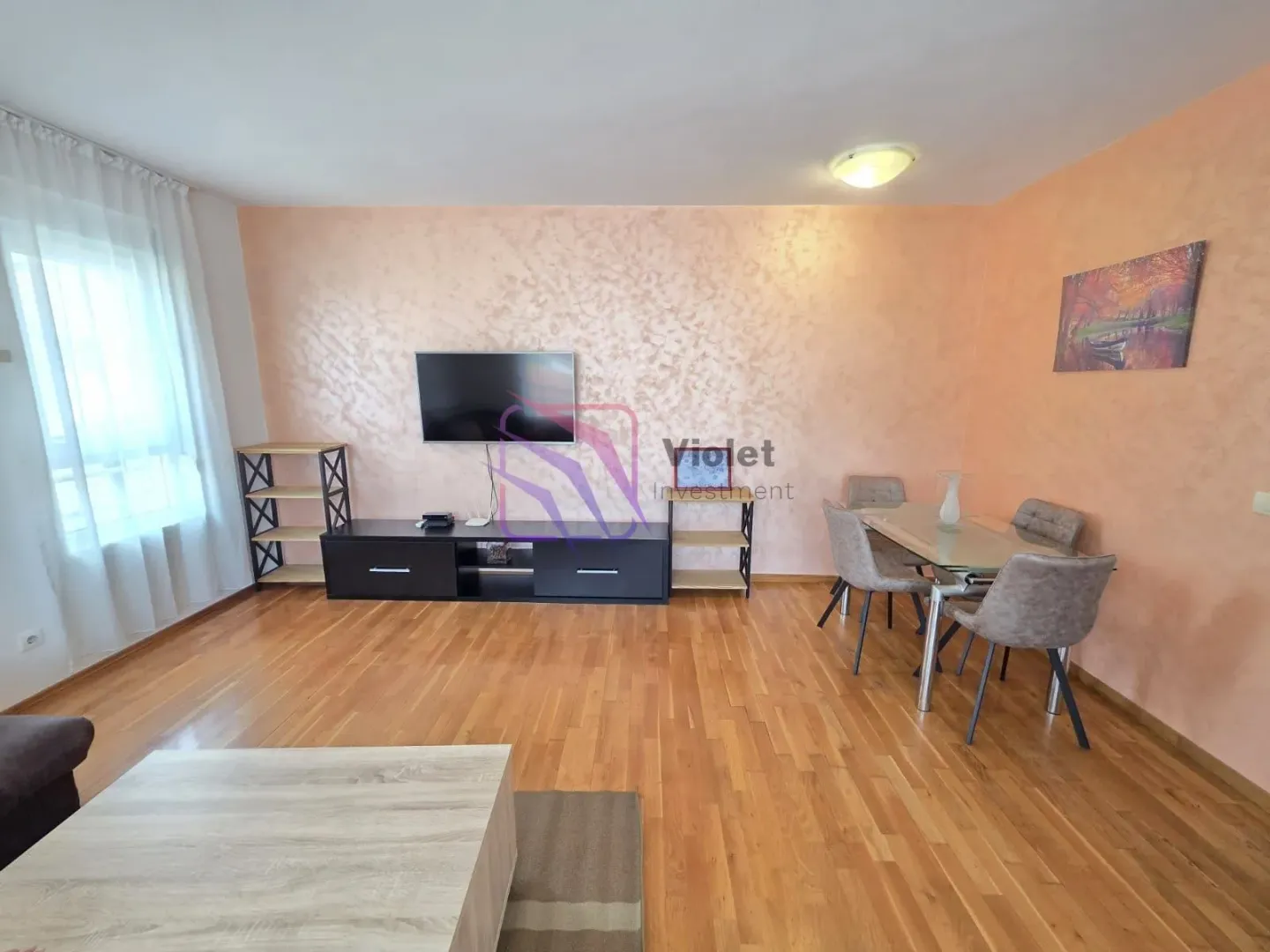 Living room with a dining area, wooden flooring, and a TV console.