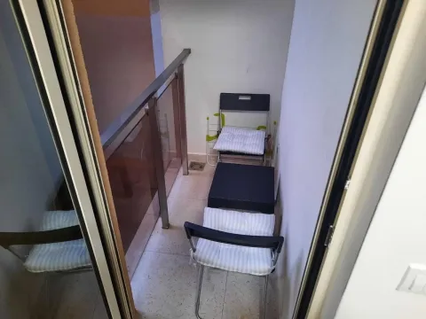 Narrow small balcony with patio furniture and glass railing. - image 12