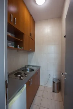 Small kitchen with wooden cabinets, a sink, and a built-in cooktop. - image 6
