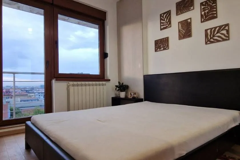 Furnished bedroom with a double bed, window, and city view.