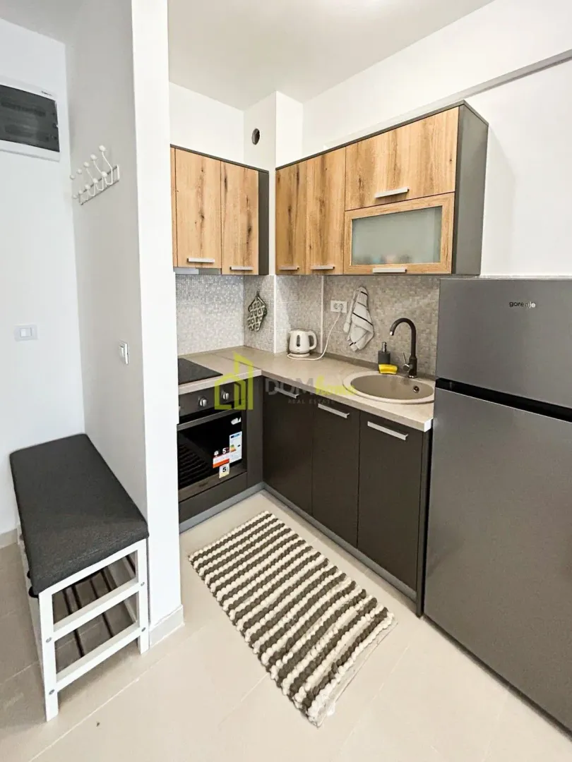 Small equipped kitchen with wooden cabinetry and a grey countertop.