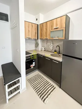 Small equipped kitchen with wooden cabinetry and a grey countertop. - image 6