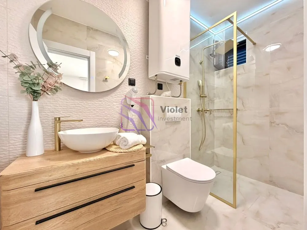 Modern bathroom with a washbasin, walk-in shower, and built-in fixtures.