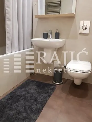 Modern bathroom with a sink, toilet, and bathtub.