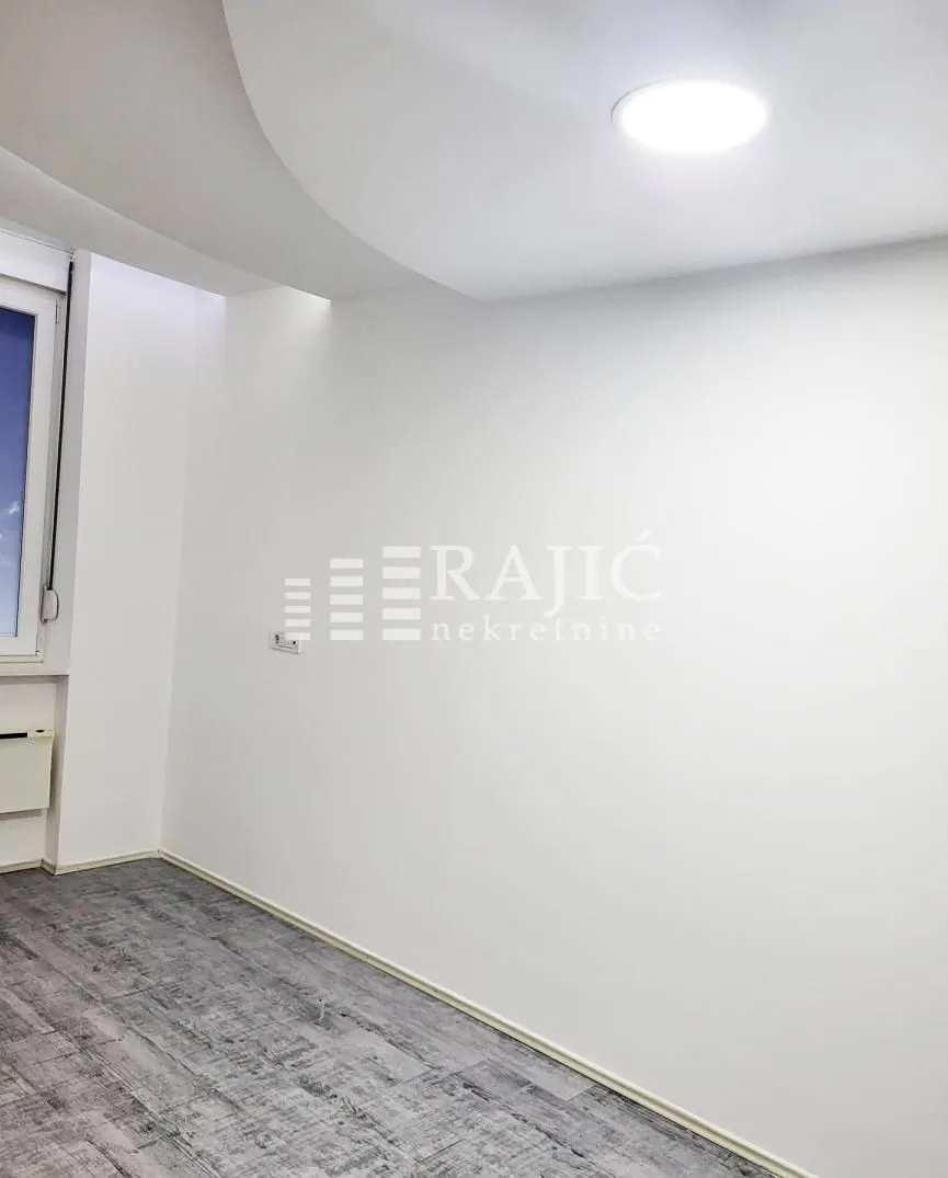 Empty bright room with white walls and gray flooring.