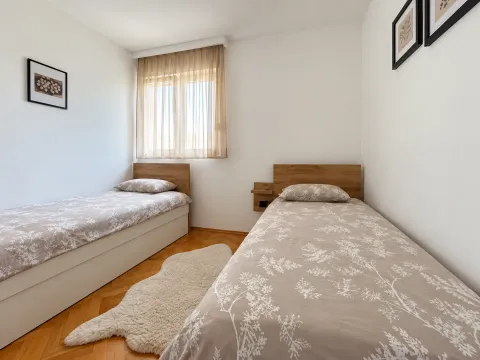 Bedroom with two single beds and wooden flooring. - image 8