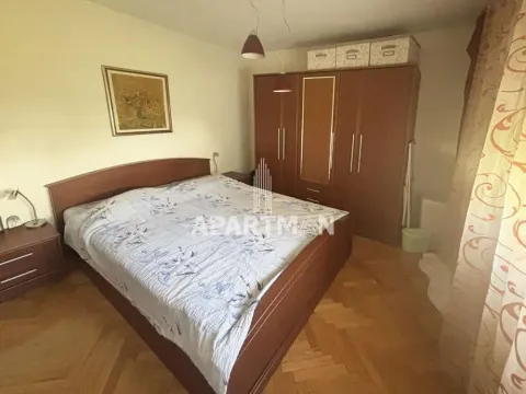 Spavaća soba sa bračnim krevetom, drvenim ormanom i parketom na podu. - image 6