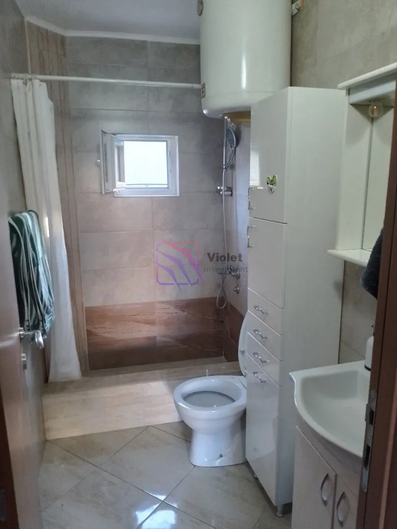 Kupatilo opremljeno tuš kabinom, umivaonikom, WC šoljom i bijelim ormarićem.
