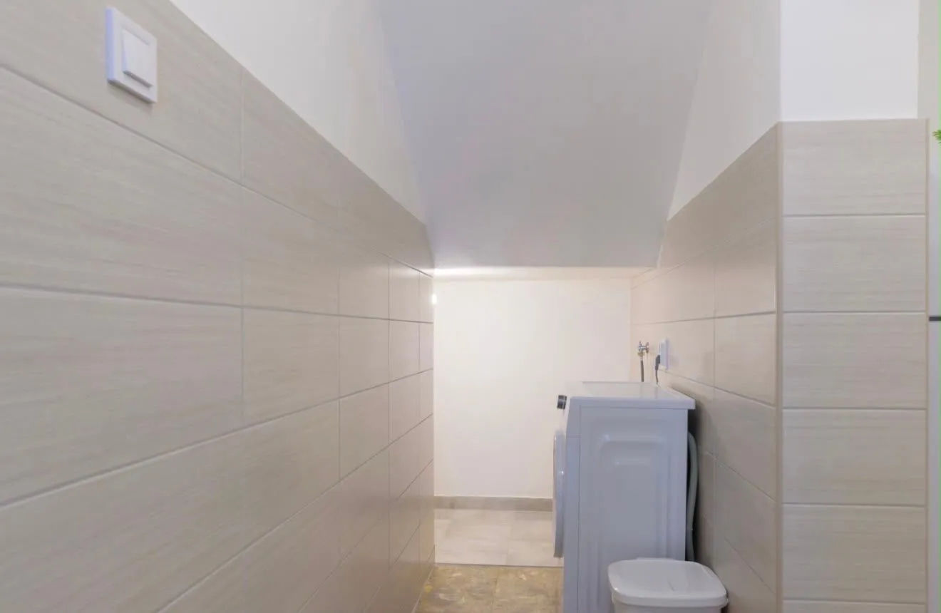 Small tiled bathroom with a washing machine.