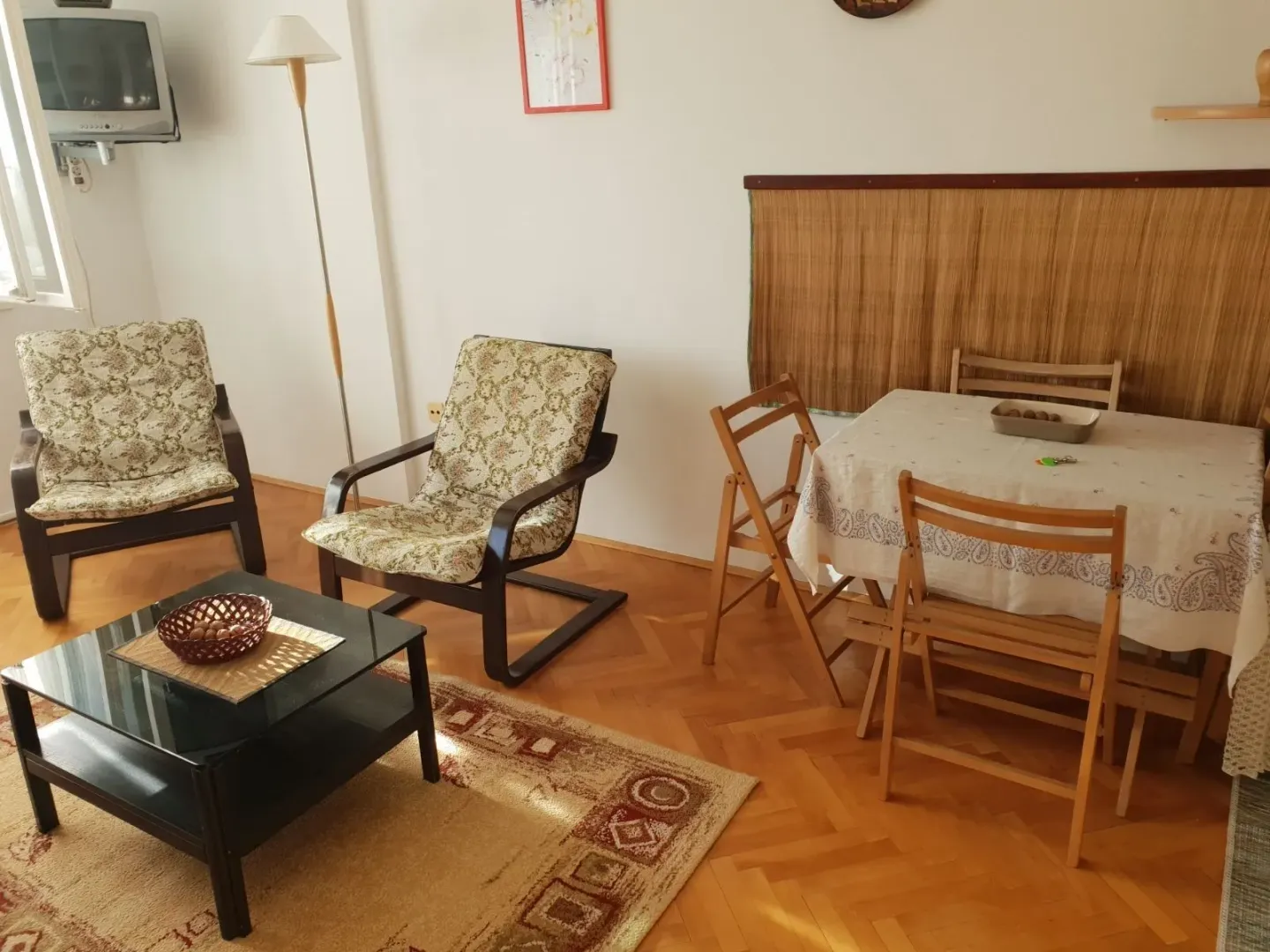 Svijetla dnevna soba sa garniturom za sjedenje i trpezarijskim stolom.