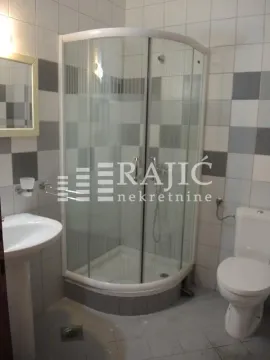Small bathroom with a shower cabin, sink, and toilet. - image 14