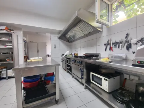 Commercial kitchen equipped with professional stainless steel appliances and work tables. - image 9