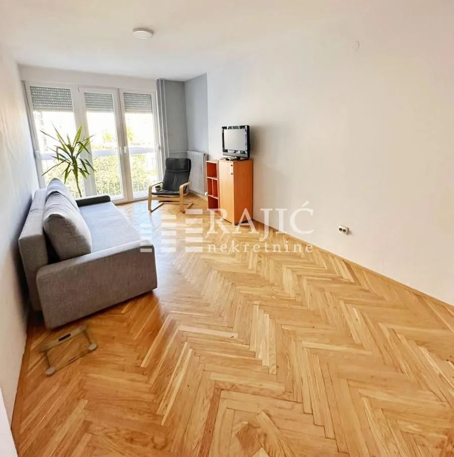 Living room with a sofa and parquet flooring.