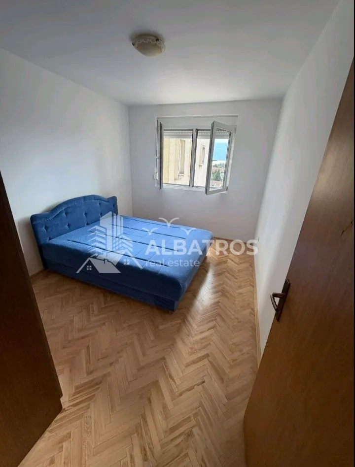 Bedroom with a blue bed and parquet flooring.