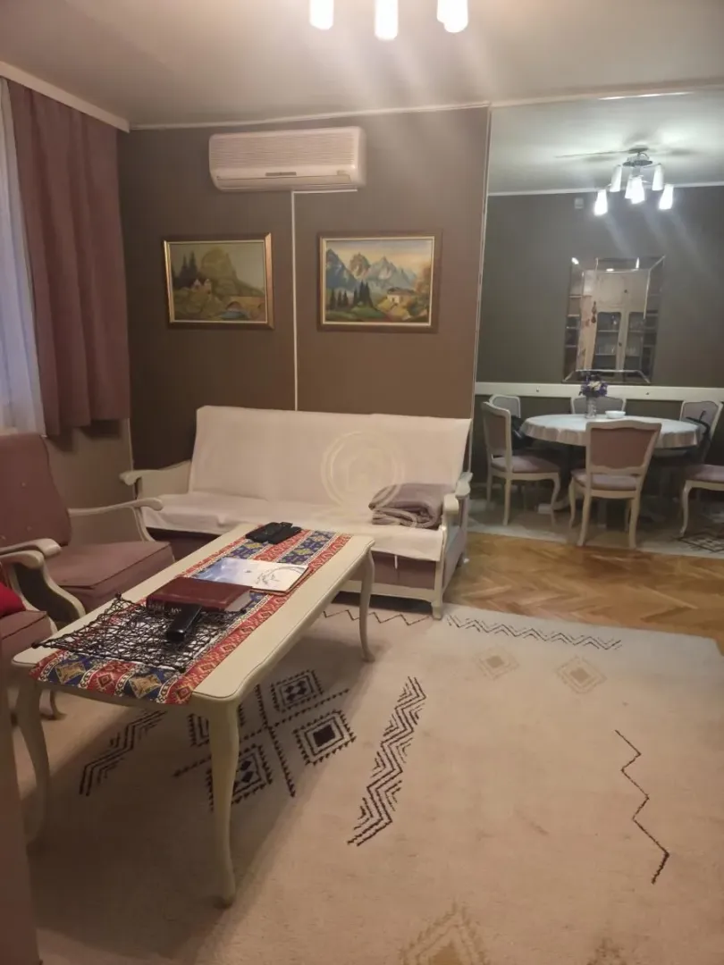 Dnevna soba sa garniturom, stočićem i trpezarijskim delom u pozadini.
