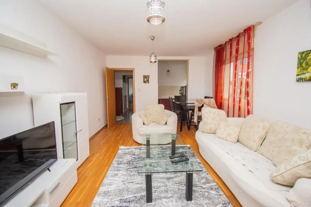 Bright living room with a seating set, a glass coffee table, and a TV.