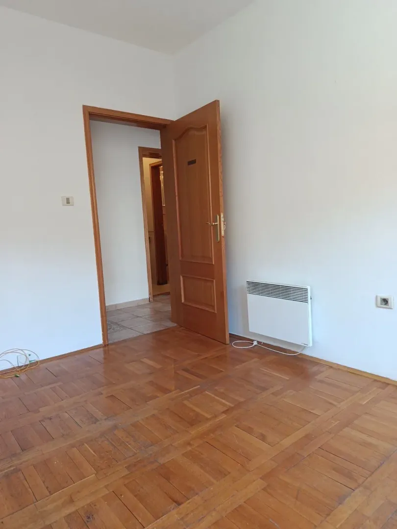 Empty room with parquet flooring and an open wooden door.