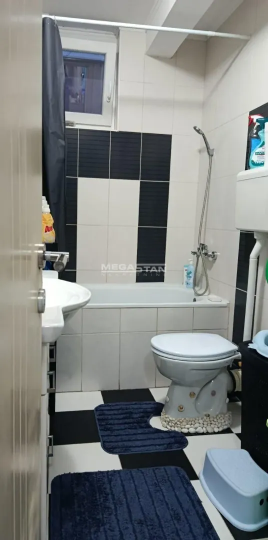 Kupatilo opremljeno kadom, umivaonikom i toaletom sa crno-belim pločicama.