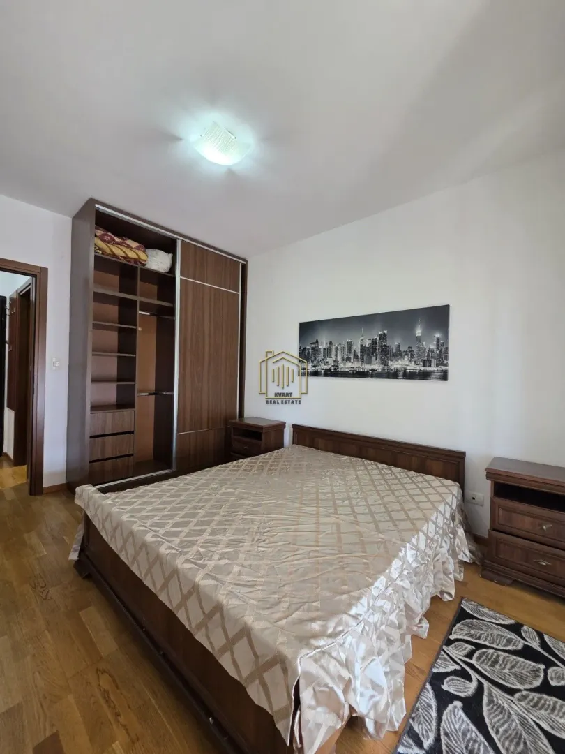 Furnished bedroom with a double bed, large wooden wardrobe, and nightstands.